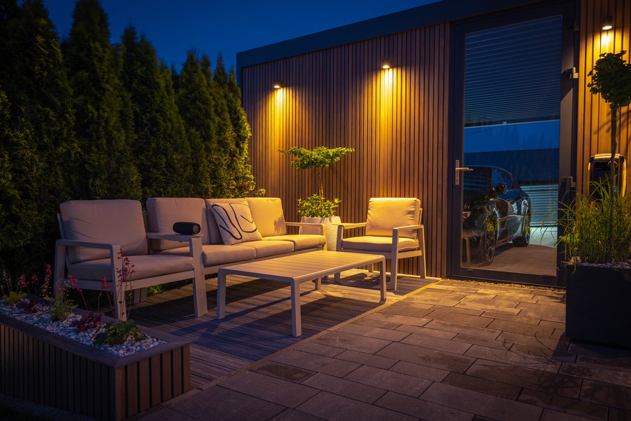  An outdoor living room with accent outdoor lighting on the wall.