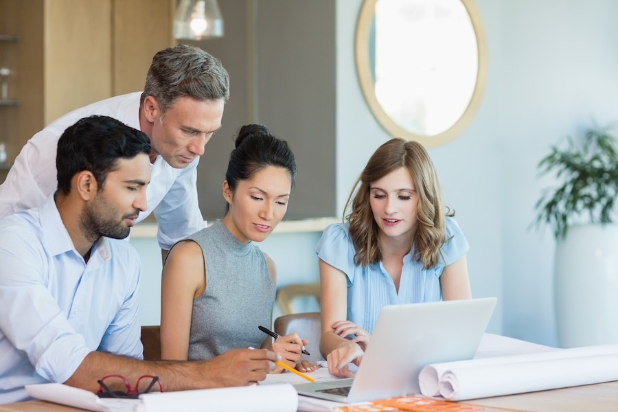 A group of people working together while looking at a laptop.