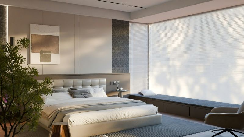A minimalist bedroom with a low platform bed, neutral tones, large window with blinds, and built-in bench seating.